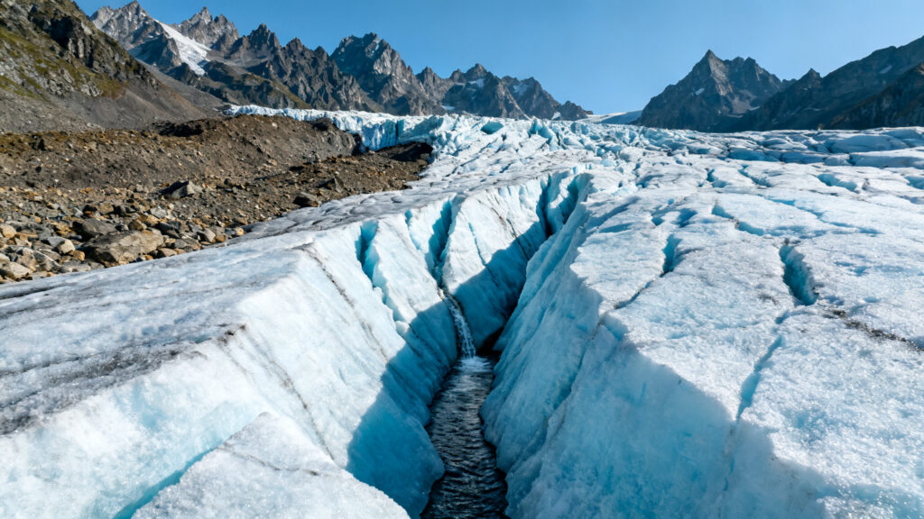 Glacier alpin en retrait avec crevasses et ruisseau de fonte